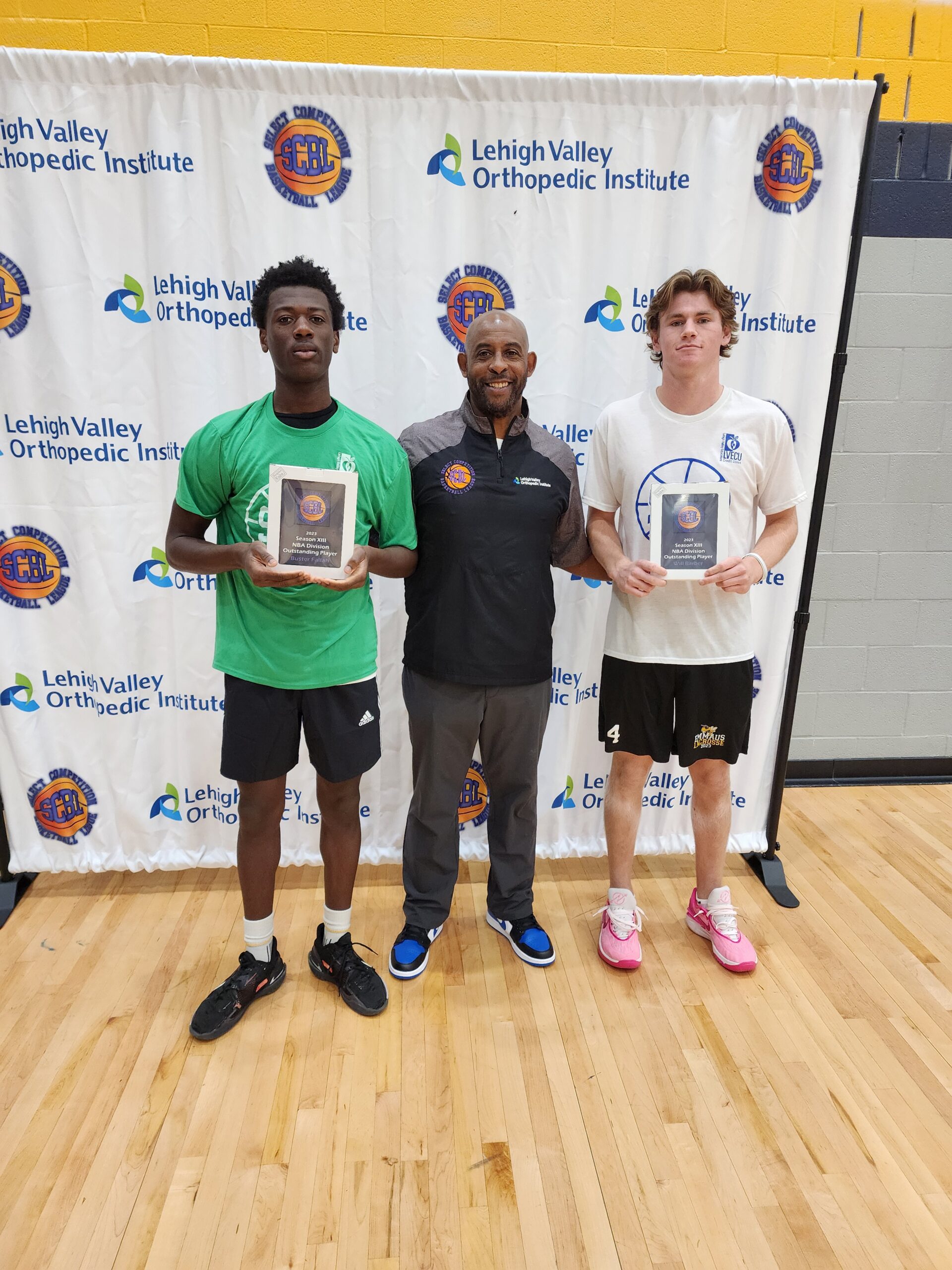 Three SCBL players and a coach stand on a court holding Season XII NBA Division Outstanding Player plaques before a Lehigh Valley backdrop.