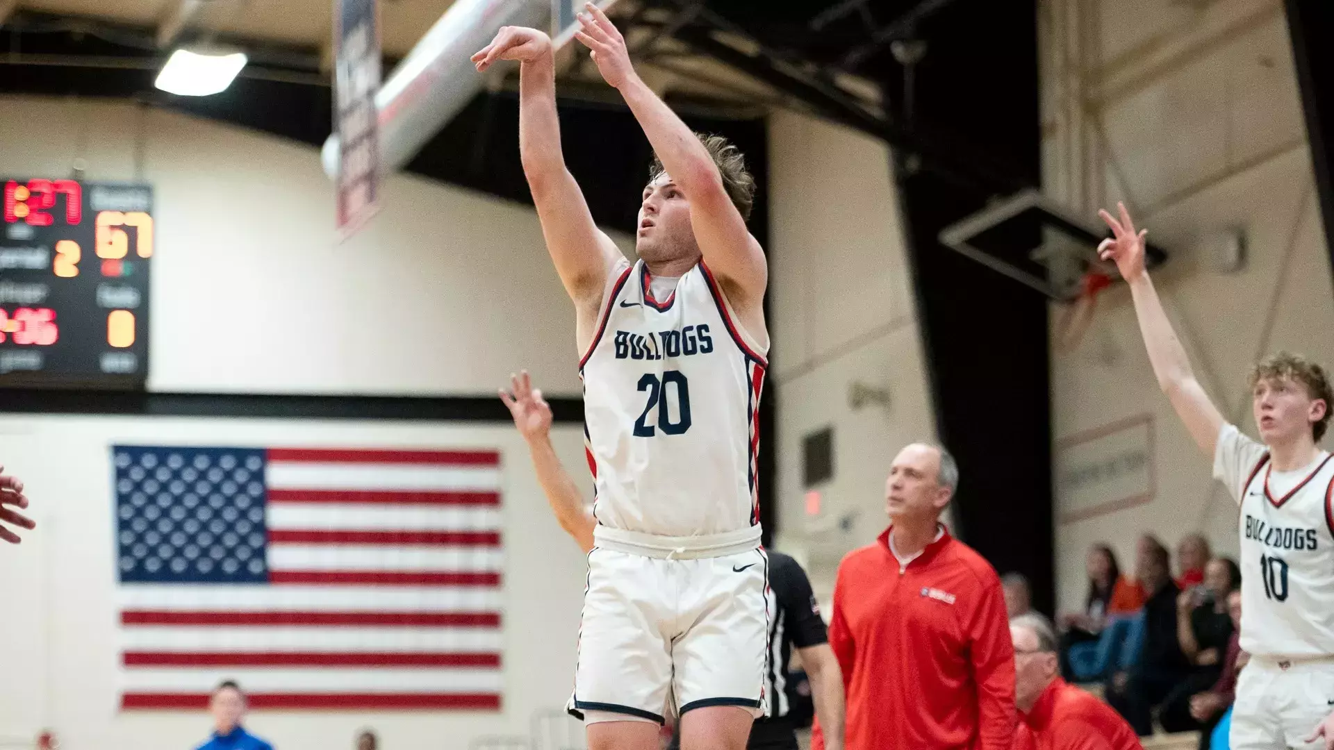 In an indoor gym, Brendan Boyle of SCBL Bulldogs rises for a jump shot during youth basketball competition as teammates and coaches watch.