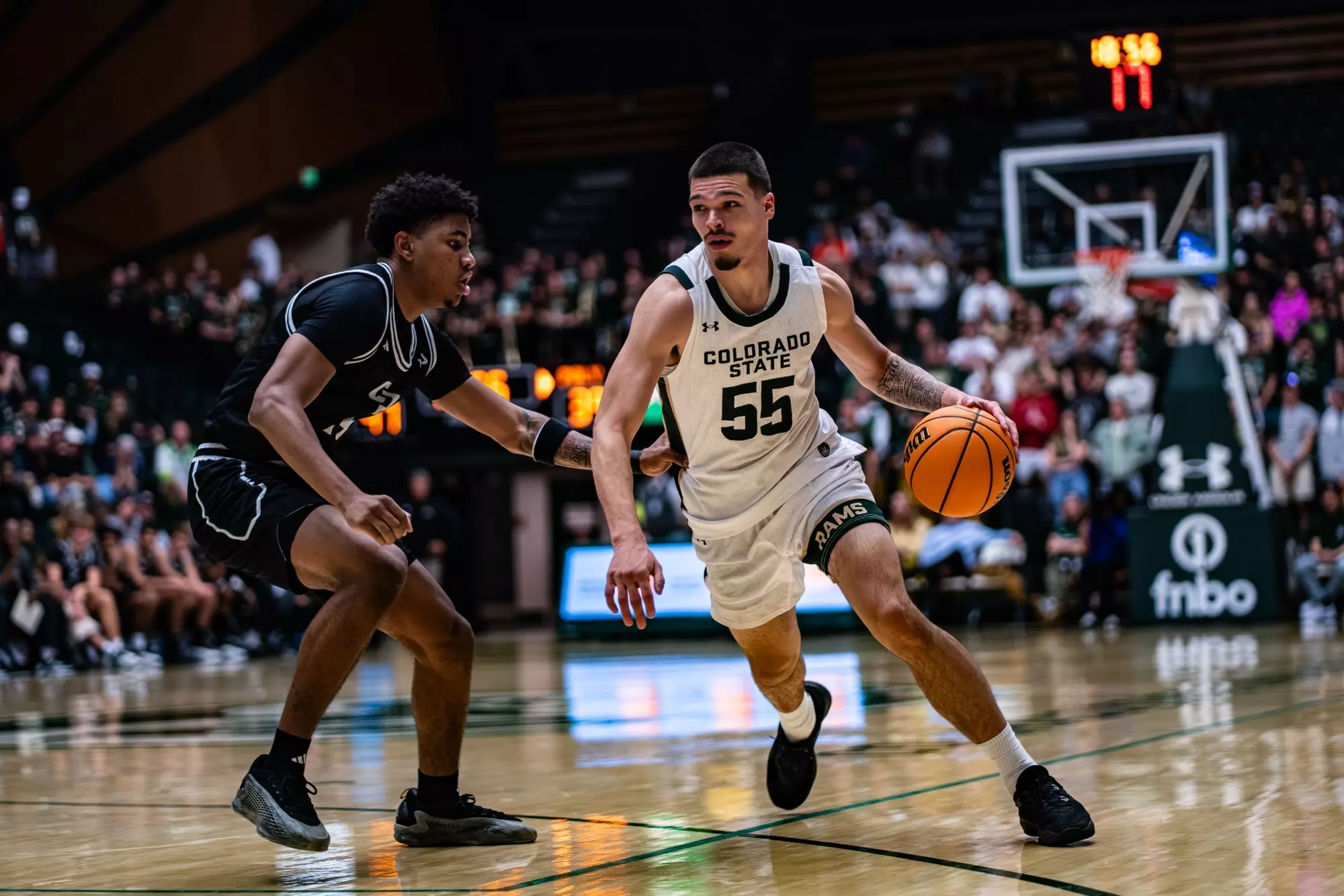 Jevin Muniz drives the ball in a Colorado State basketball game, guarded closely by a defender during fast-paced college action on the court.