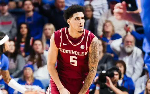 During SCBL youth basketball coverage, Kobe Magee wears a maroon Seminoles jersey as he moves on court, with a packed crowd in the background.