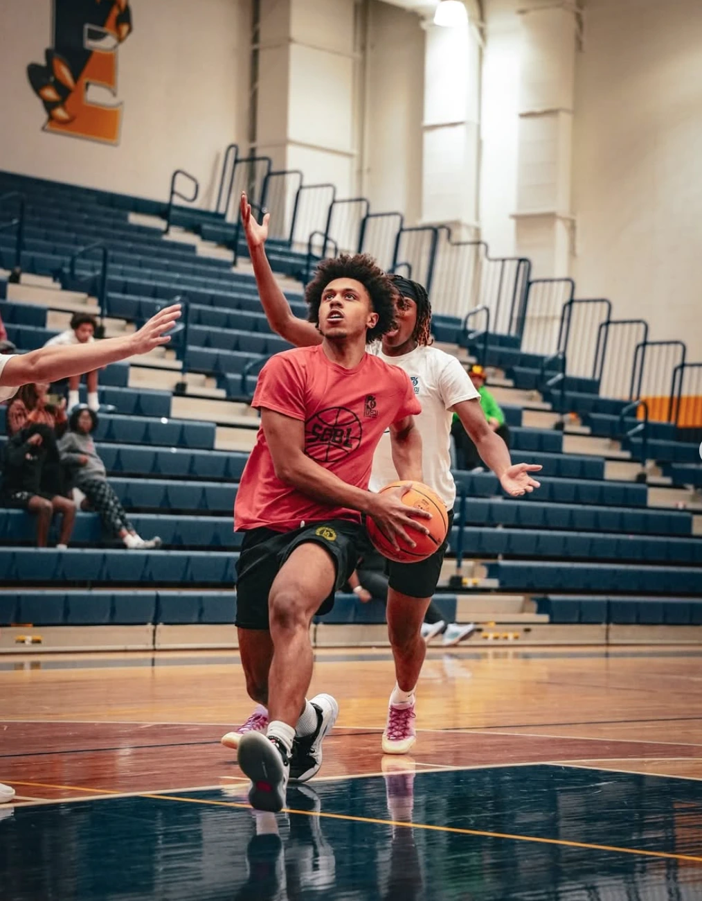 Inside SCBL's Programs page, a player drives to the basket during a youth basketball game, with teammates and defenders contesting the play.